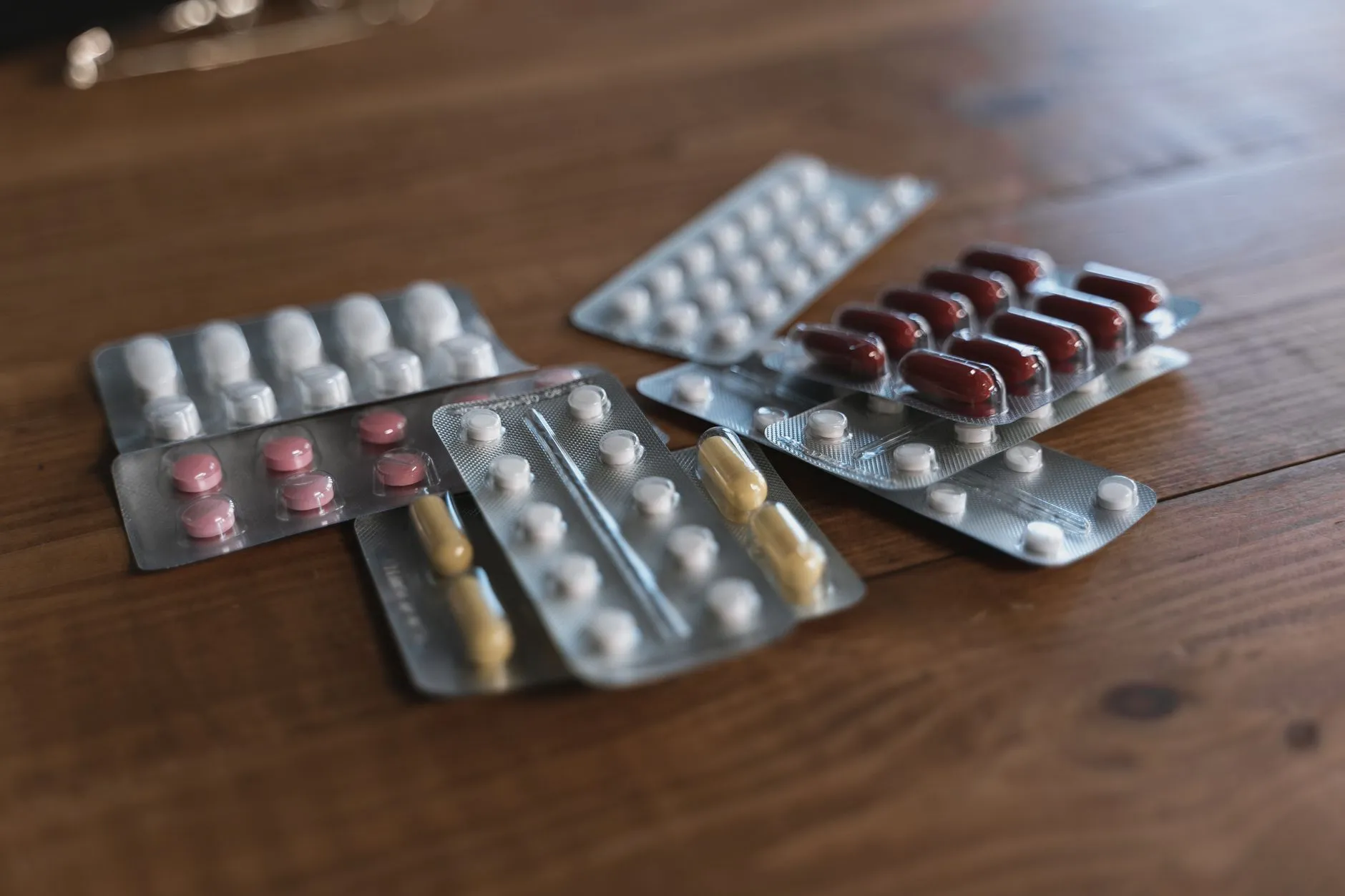 Các vỉ thuốc viên nén và viên nang đặt trên mặt bàn gỗ.