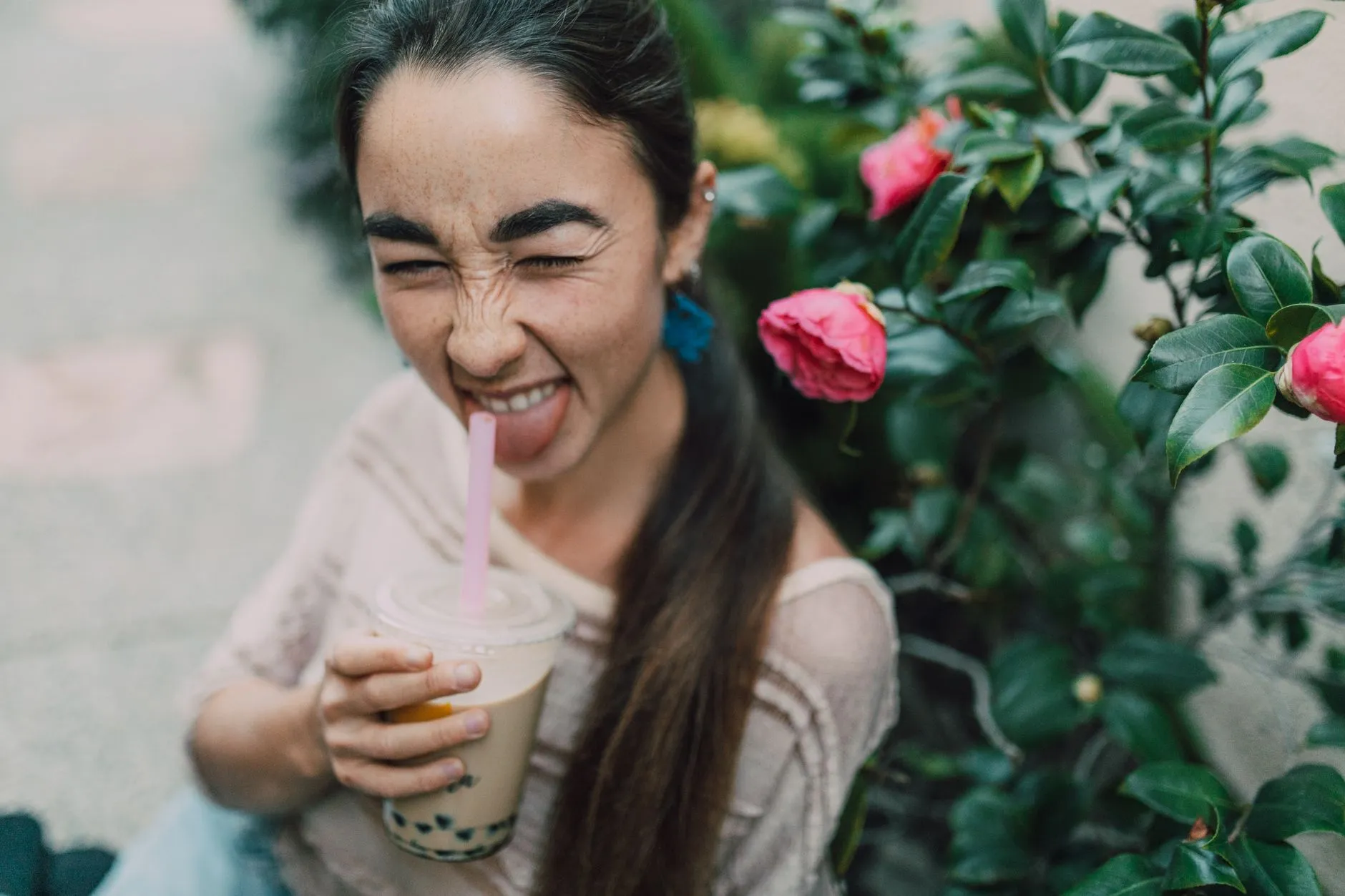 Một phụ nữ trẻ cầm ly trà sữa và ngần ngại nhìn vào đó.