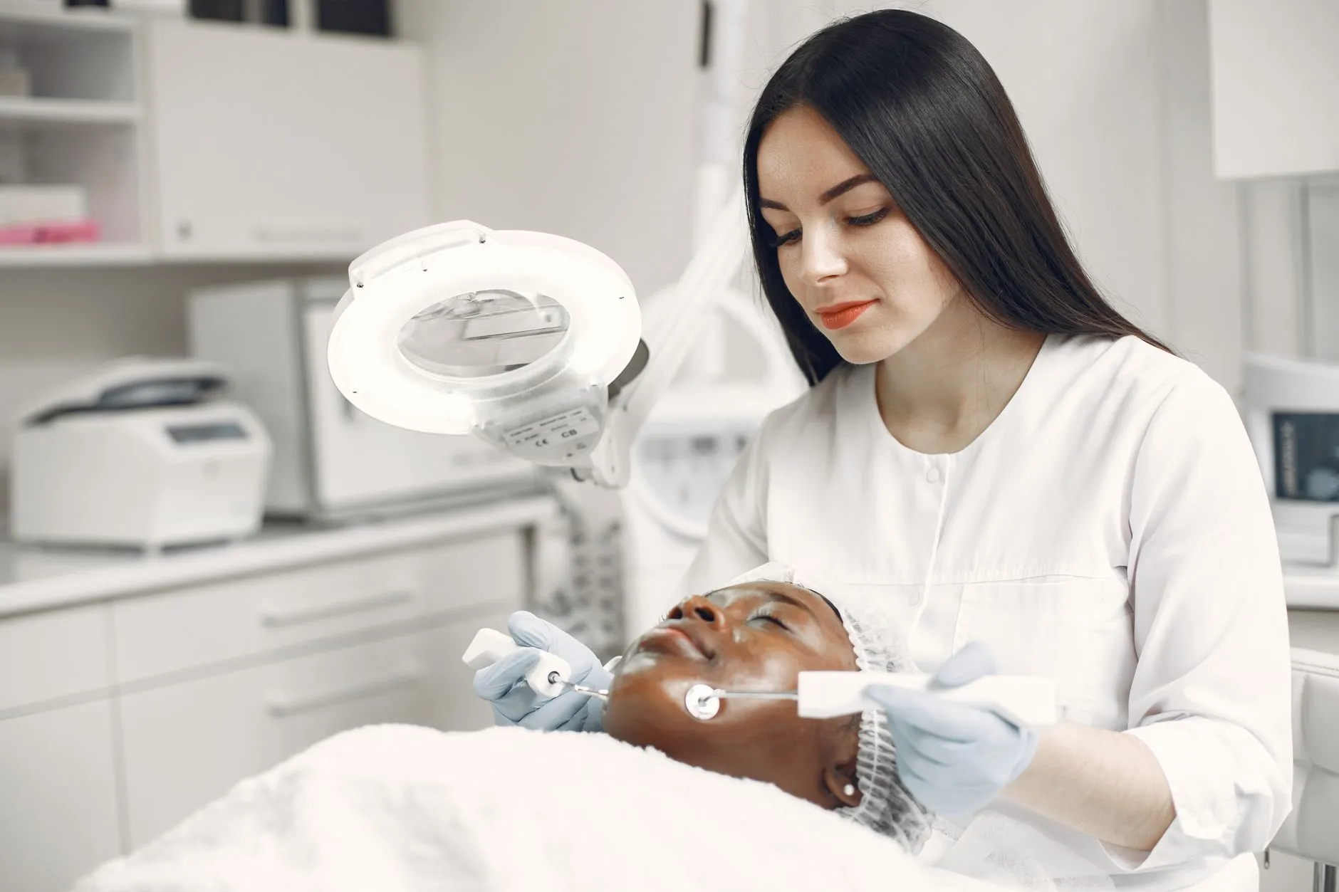 Nhân viên y tế soi và đánh giá vùng da mặt cho người bệnh dưới đèn soi trong phòng điều trị.