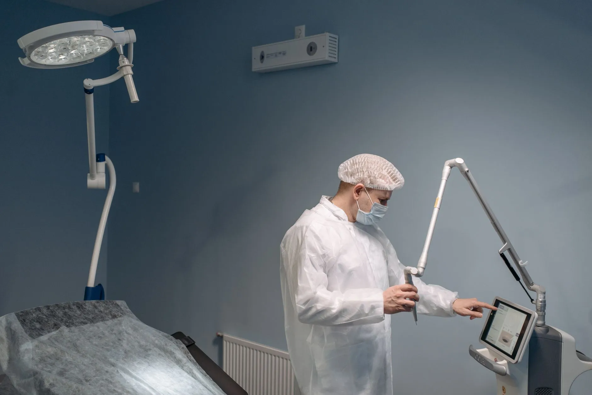 Nhân viên y tế chỉnh thông số trên máy laser trong phòng thủ thuật.