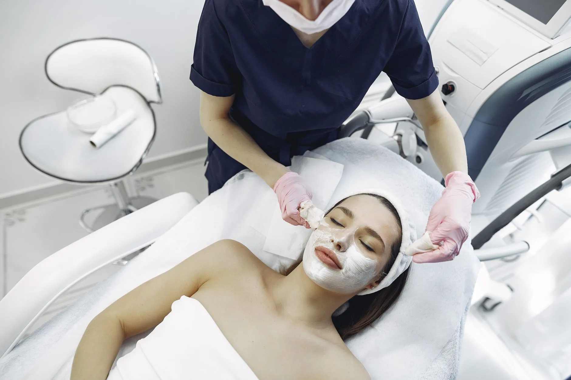Nhân viên y tế đeo găng thao tác trên mặt một người bệnh nữ đang nằm trong phòng điều trị.