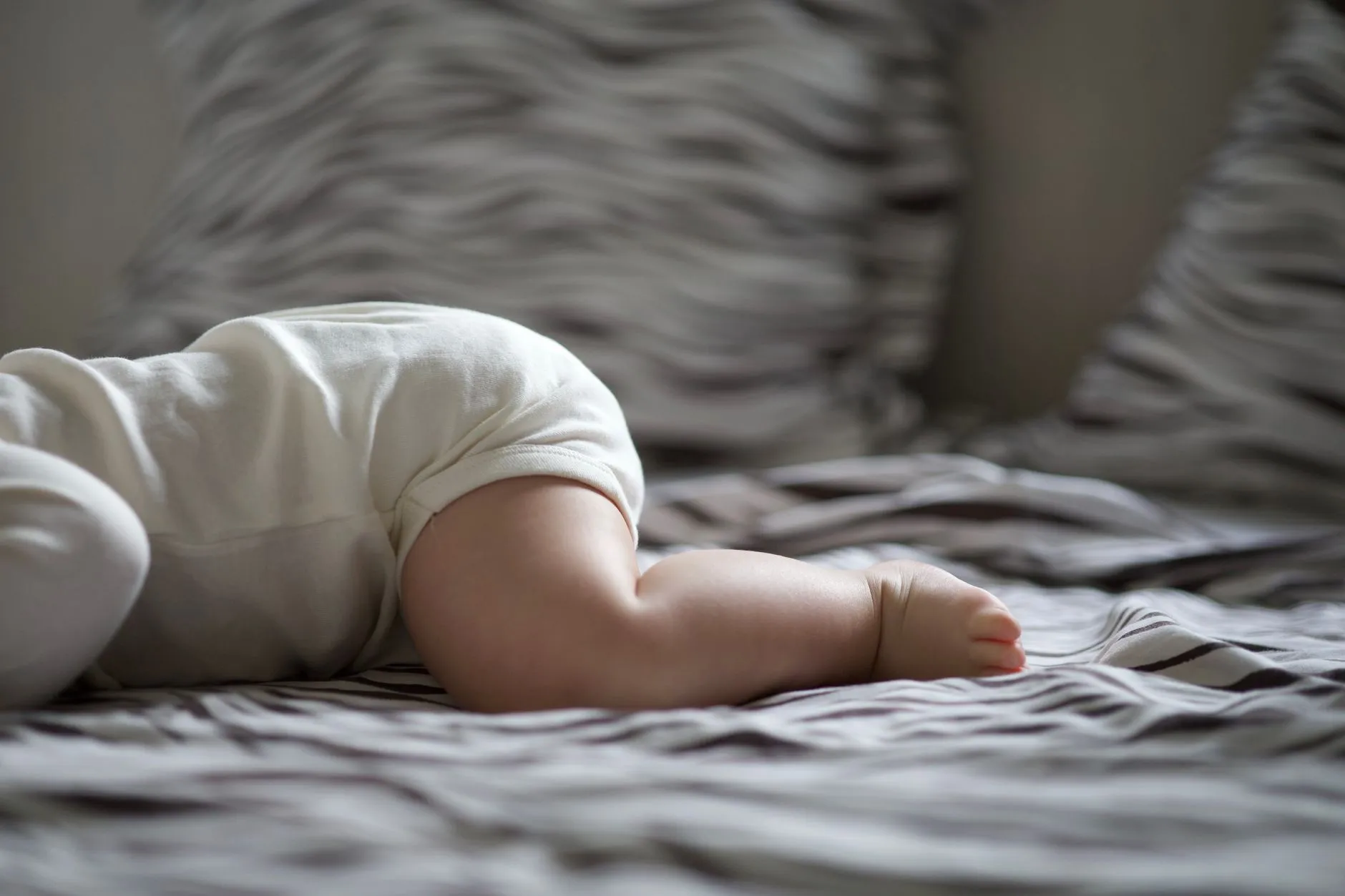 Em bé mặc áo mỏng nằm chơi trong phòng thoáng mát dưới ánh sáng tự nhiên.