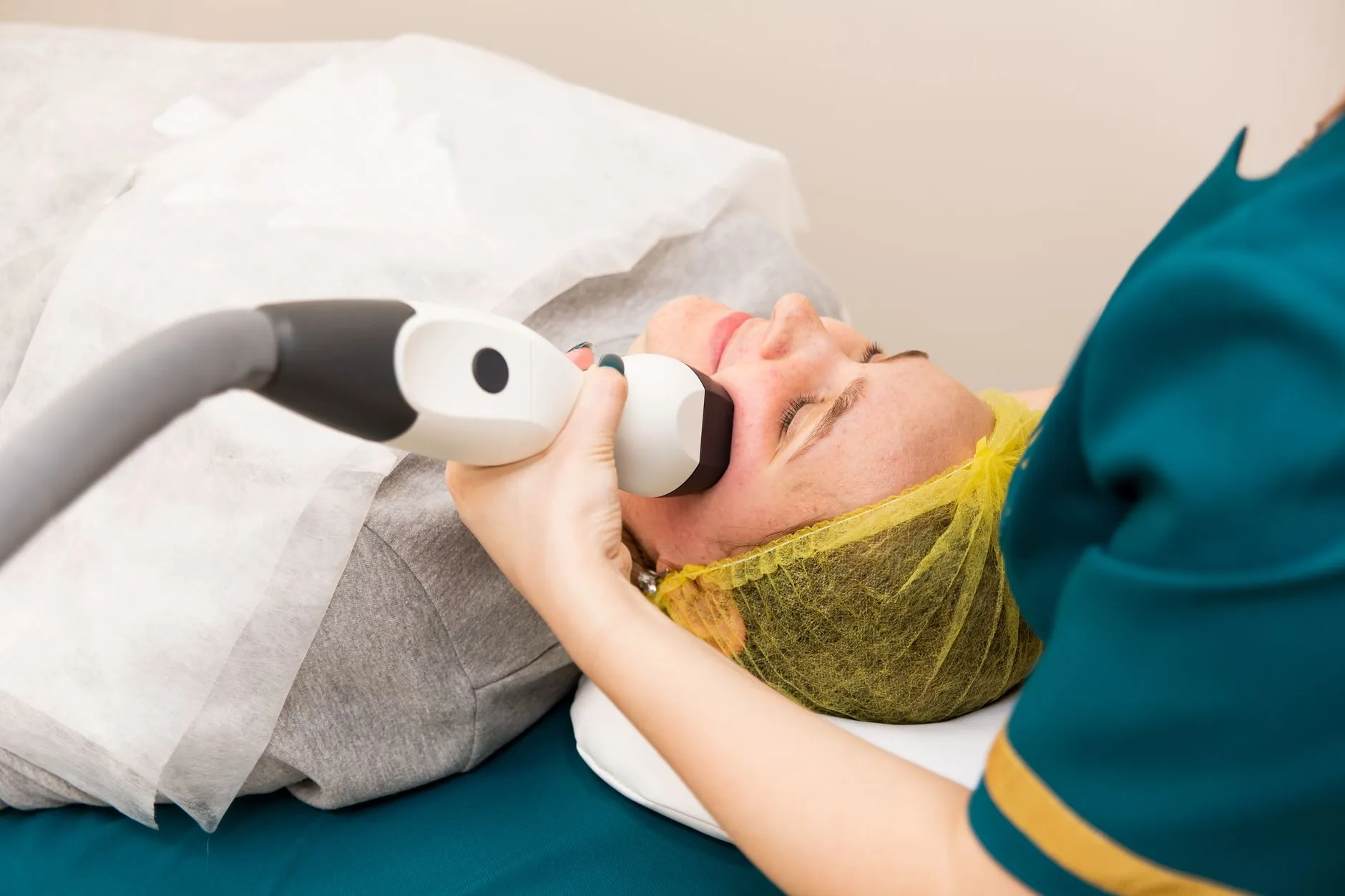 Kỹ thuật viên đưa đầu phát của thiết bị trên vùng gò má người bệnh đang nằm trên giường thủ thuật.