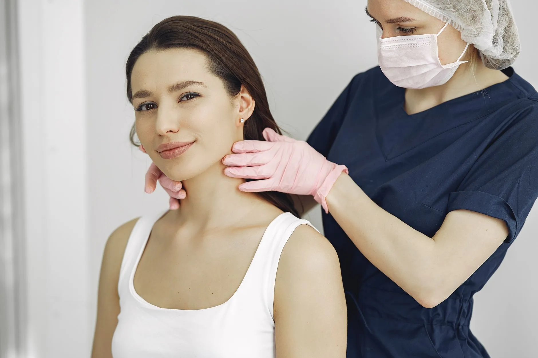 Bác sĩ đeo găng đang khám vùng sẹo trên vai một người bệnh trong phòng khám.