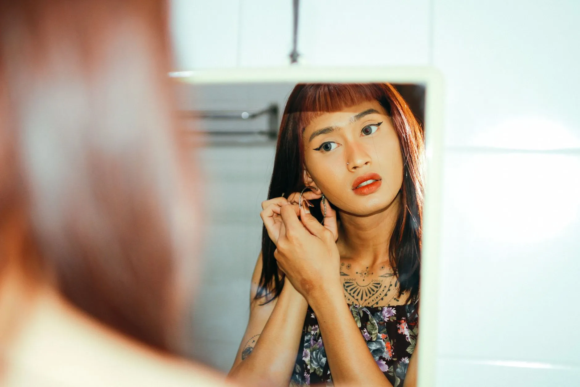Một phụ nữ trẻ soi gương quan sát vùng da đỏ quanh miệng và cánh mũi.
