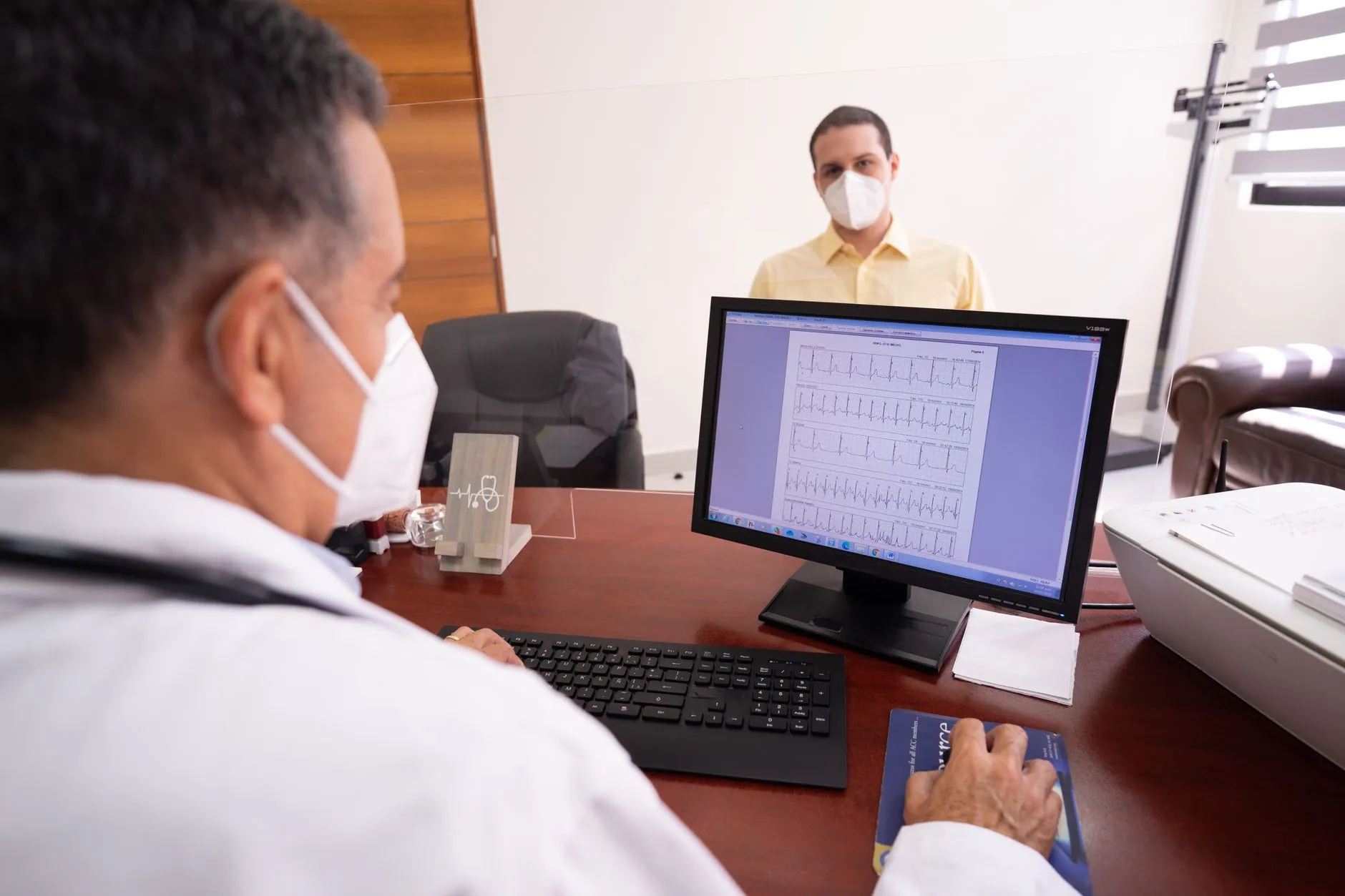 Bác sĩ trao đổi với bệnh nhân bên tờ kết quả xét nghiệm trong phòng khám.