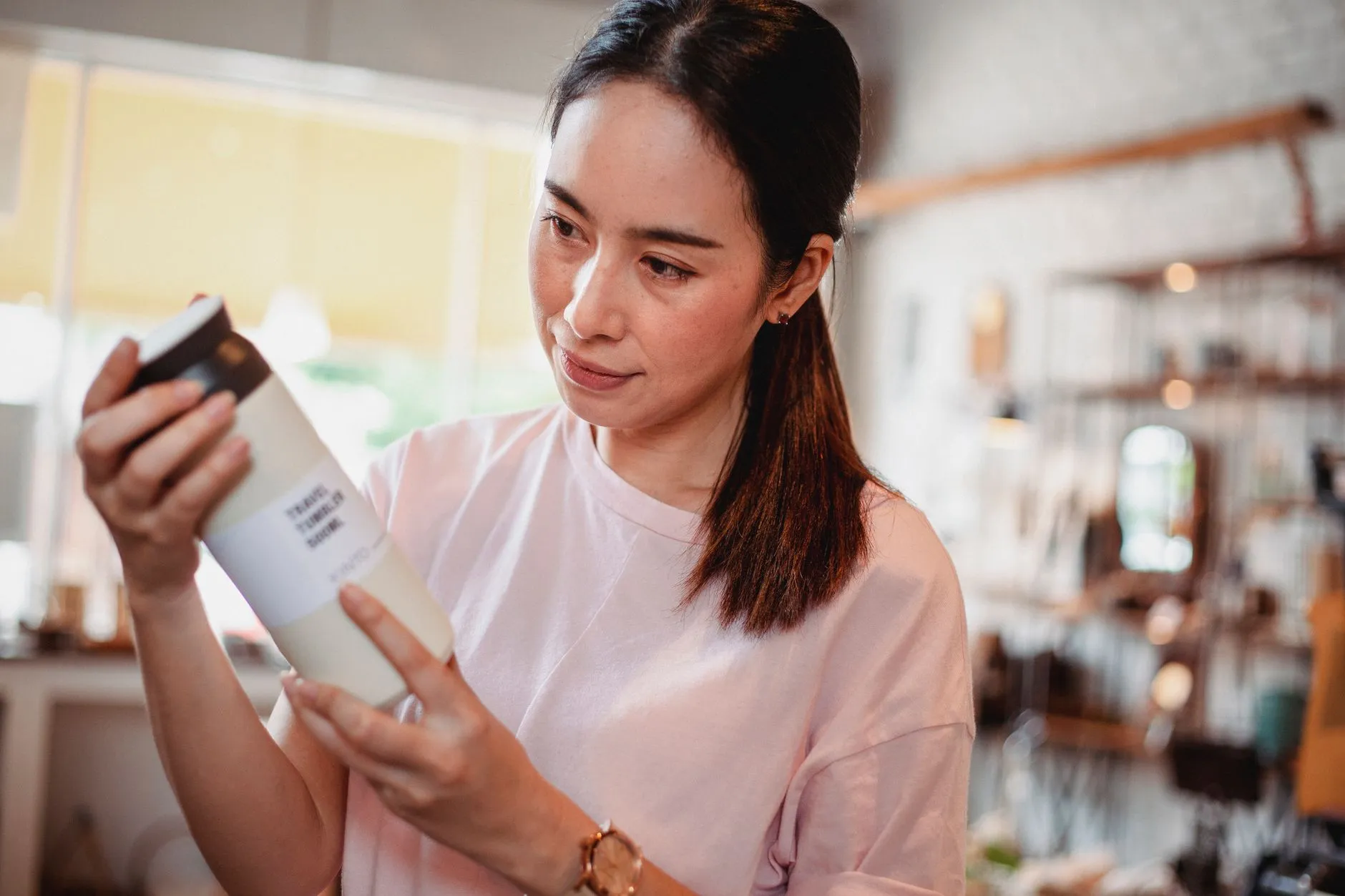 Người phụ nữ cầm một lọ sản phẩm và đọc nhãn thành phần.