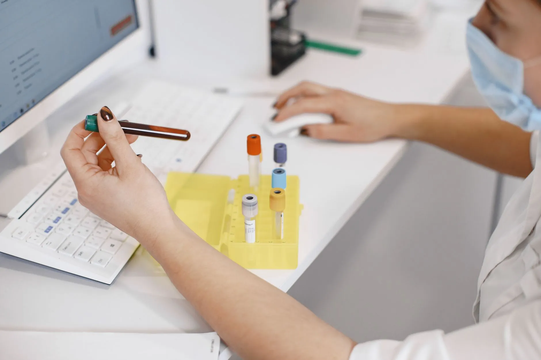 Kỹ thuật viên thao tác với mẫu máu bên máy xét nghiệm trong phòng lab.